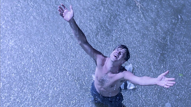 man with arms up in the rain