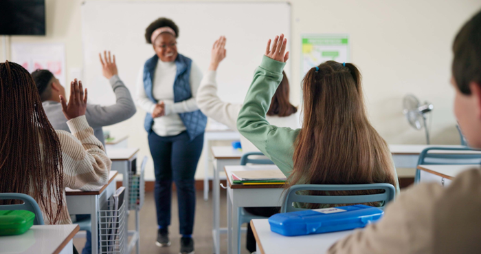 School teacher in front of a class looking happy